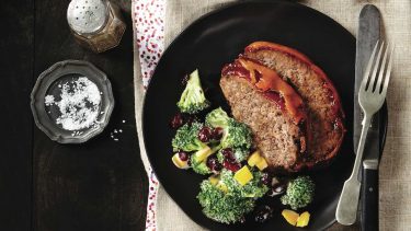 Meatloaf and broccoli salad on black plate.