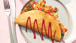vegan omurice on round neutral plate on pink background