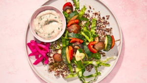vegan vegetable kebabs with lemon-garlic sauce and quinoa on a neutral round plate