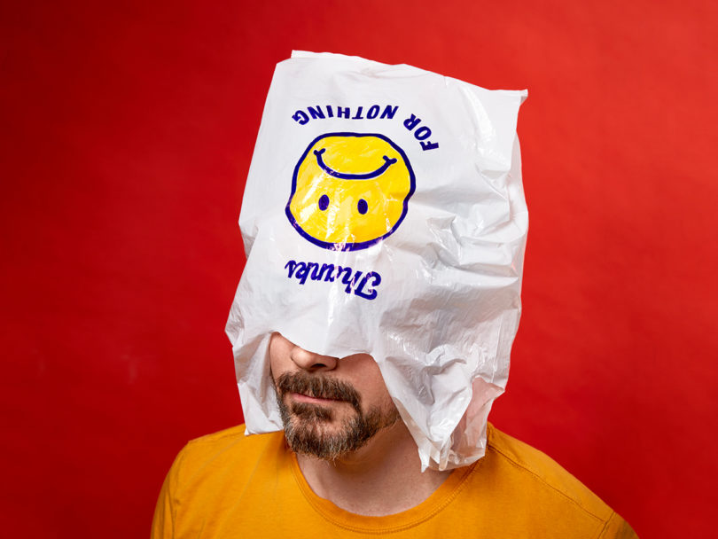 A man with a beard and yellow shirt with a plastic bag over his head that reads 