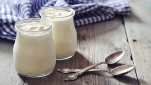 Homemade yogurt in glass jars with spoons on a wooden background