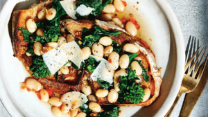 Toast with white beans, broccolini and cooked tomatoes on a plate.
