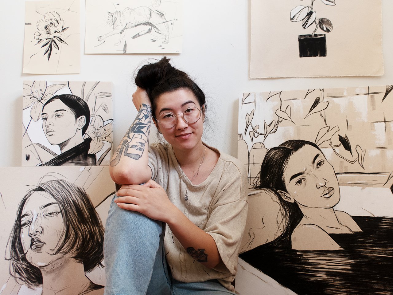 Canadian artist Katie So sitting in front of several of her paintings to illustrate an article on female artists in Canada.