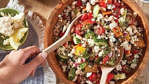 verhead shot of a wooden bowl filled with Greek Salad with Toasted Buckwheat