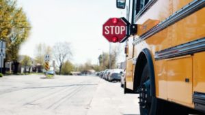 A stopped school bus with a stop sign for a column on school restarting in Ontario