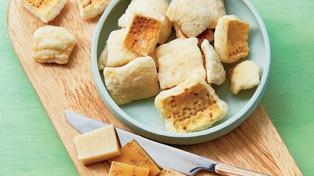Parmigiano-Reggiano rind croutons on a plate and wooden board.
