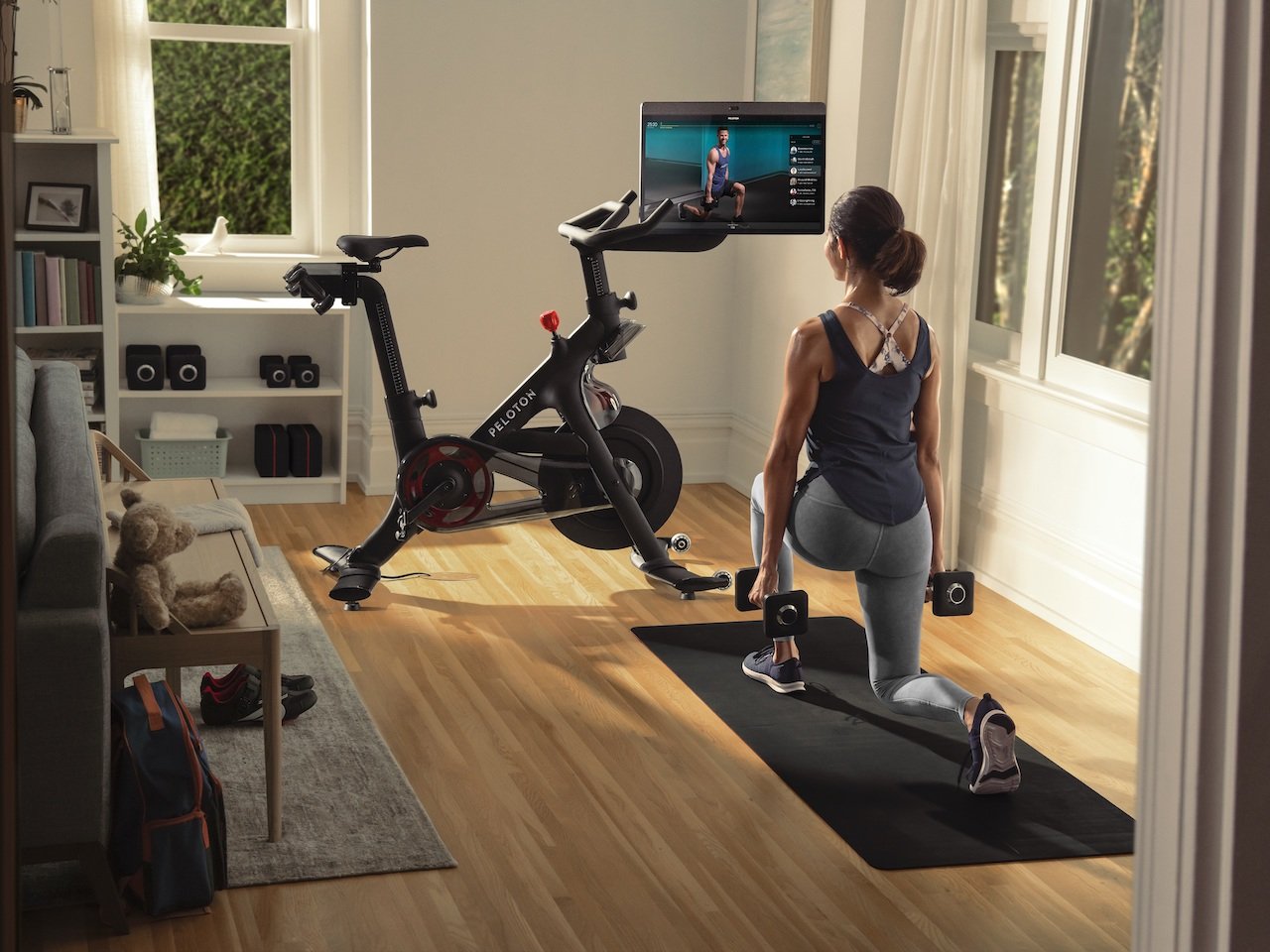 A woman doing a strength workout on the floor while looking at her Peloton screen