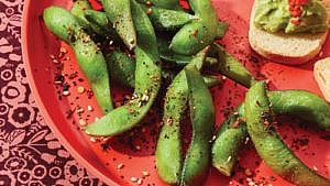 Close up of spicy edamame on sunset-coloured plate