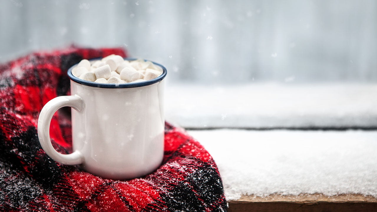 hot chocolate and a blanket in the snow for a post on classic hot cocktail recipes for winter