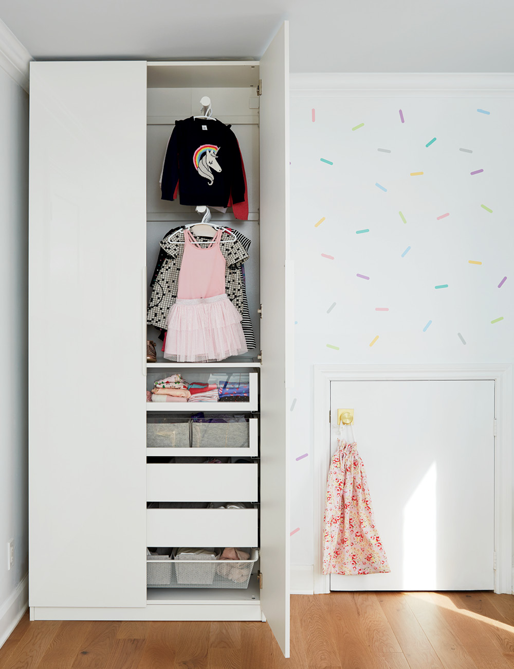 A white IKEA wardrobe filled with children's clothing