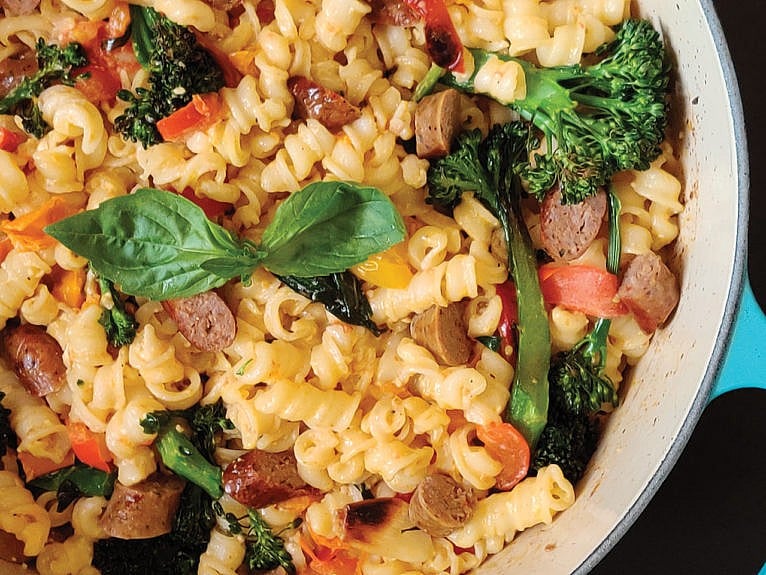 Pot of creamy pasta with sausage, tomato and broccolini.