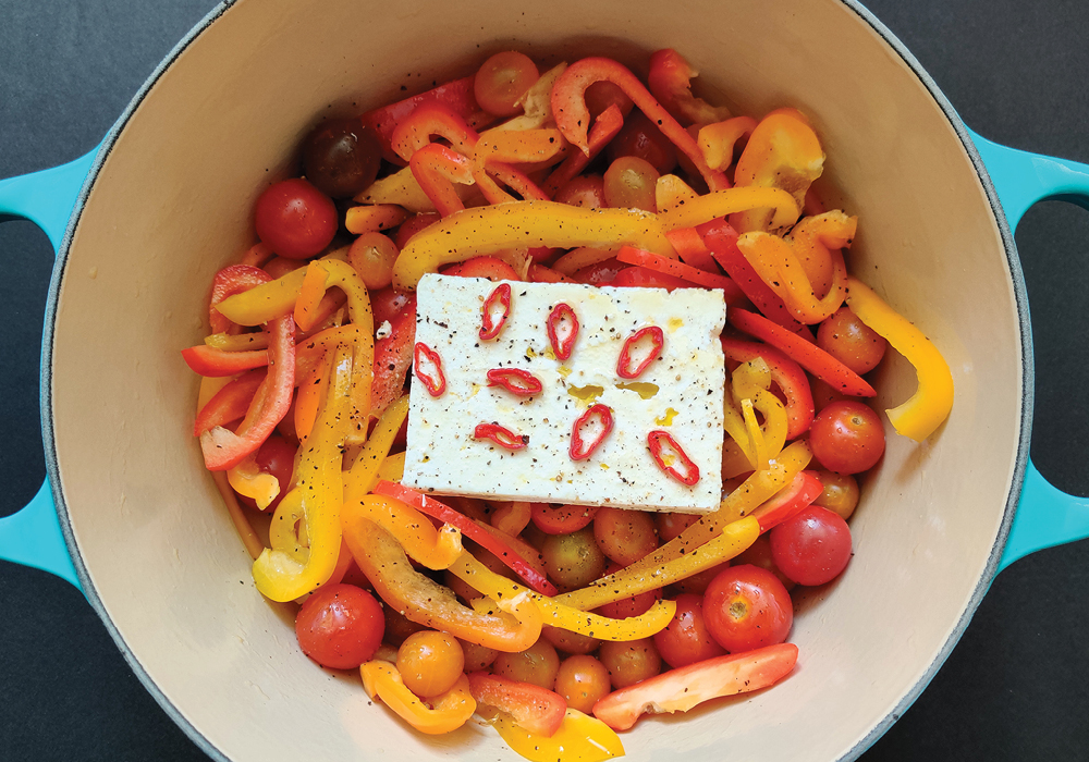 Uncooked tomatoes, peppers and feta seasoned in a pan together.