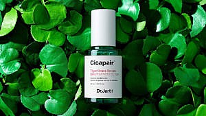 A bottle of cica serum against a green leafy background for an article about skincare ingredient cica.