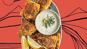 A photo of crispy fried pickerel on an oval plate with lemon wedges and tartar sauce