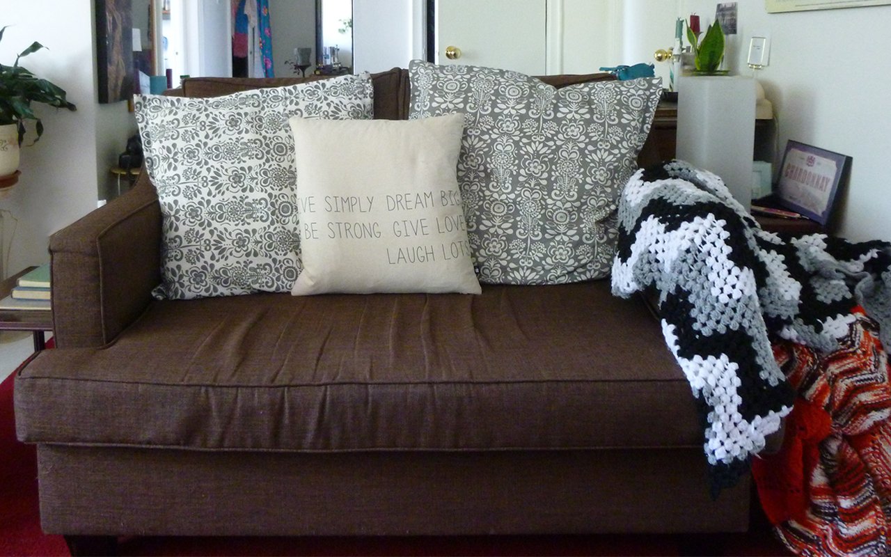 A brown couch with pillows in an apartment furnished for free through curbing.