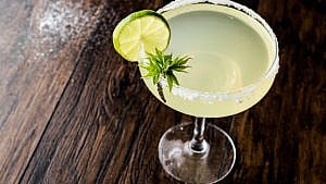 A classic margarita cocktail viewed from above in a coupe glass rimmed with salt and adorned with a lime wedge