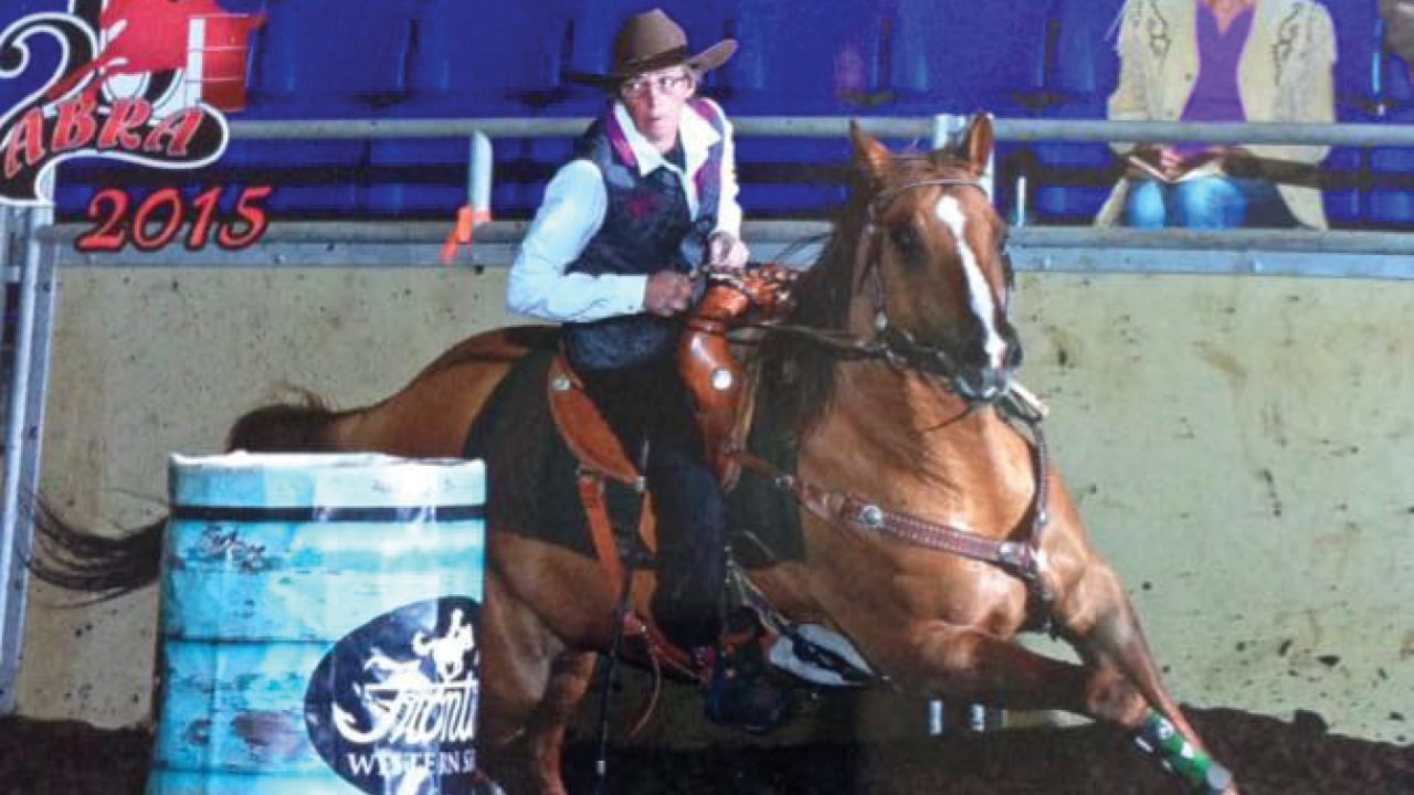 Helen Naslund taking part in a barrel racing event on a bay horse