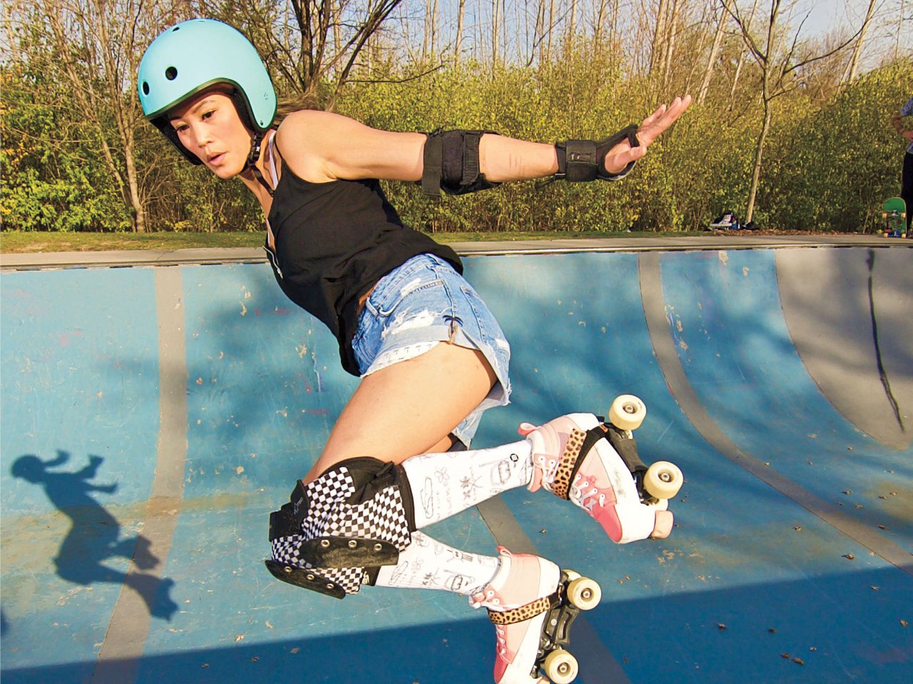 A woman in helmet, elbow, wrist, ankle and knee pads grabbing some air in her roller skates