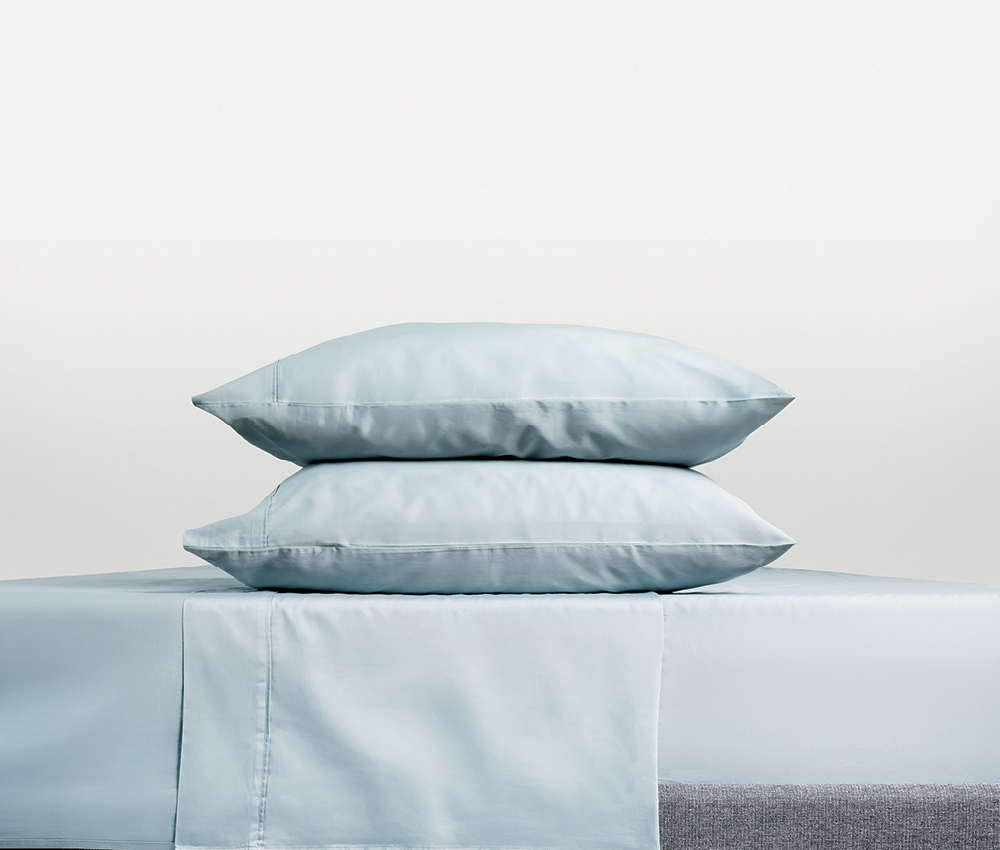 Light blue Endy bed sheets on two pillows and a bed