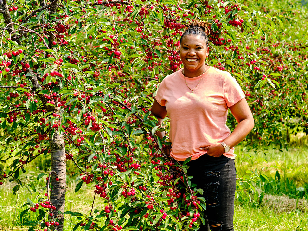 Felena Pereira stands beside a tree with fruit