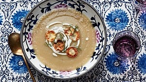 Jerusalem artichoke and potato soup in a bowl with mushrooms and creme fraiche on top