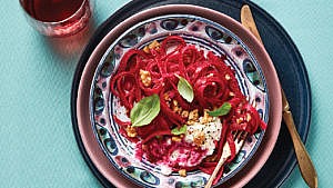 Beet pasta with creamy ricotta, walnuts and basil in a colourful plate