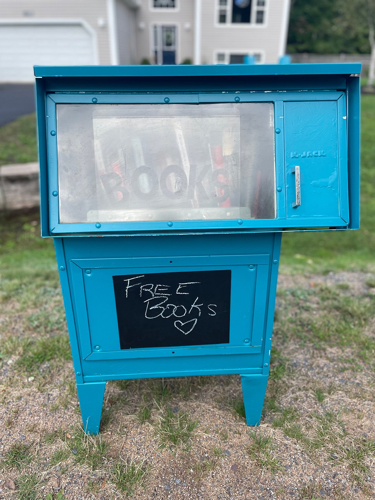 A close up of a blue Little Free library box, with a chalkboard sign saying "free books" with a heart drawn under it