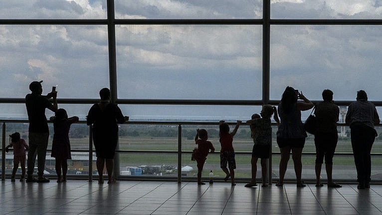 Families watch planes on the tarmac at Johannesburg's OR Tambo's airport, Nov. 29, 2021. WHO urged countries around the world not to impose flight bans on southern African nations due to concern over the new Omicron variant. (AP Photo/Jerome Delay)