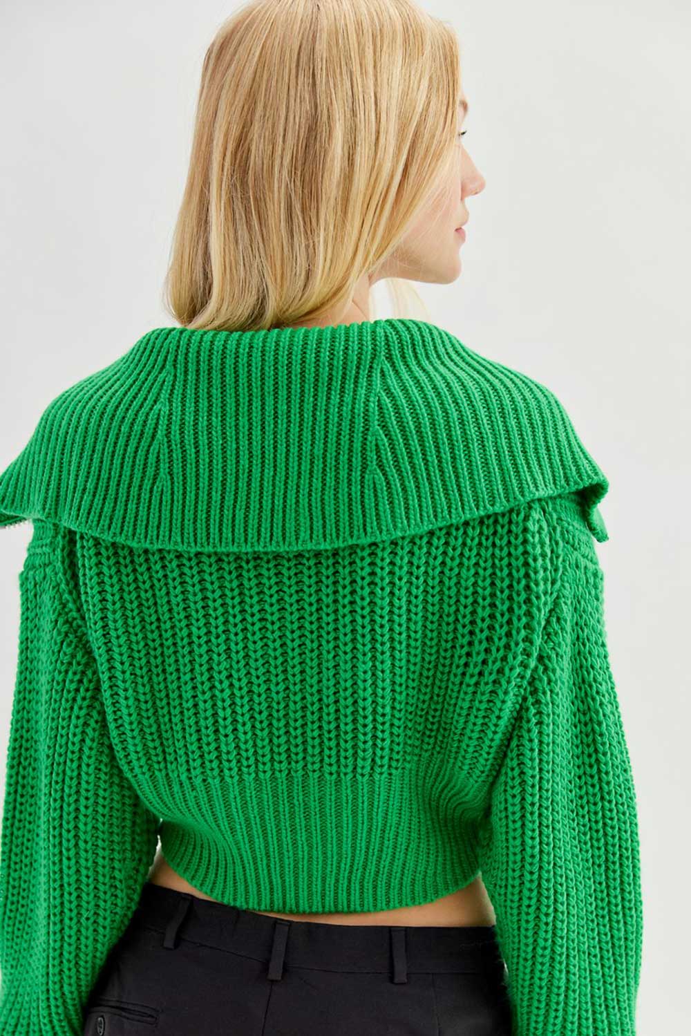 A model seen from the back wearing a knit bright green cardigan from Urban Outfitters with a large collar.