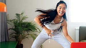 A smiling woman works out while looking at her laptop