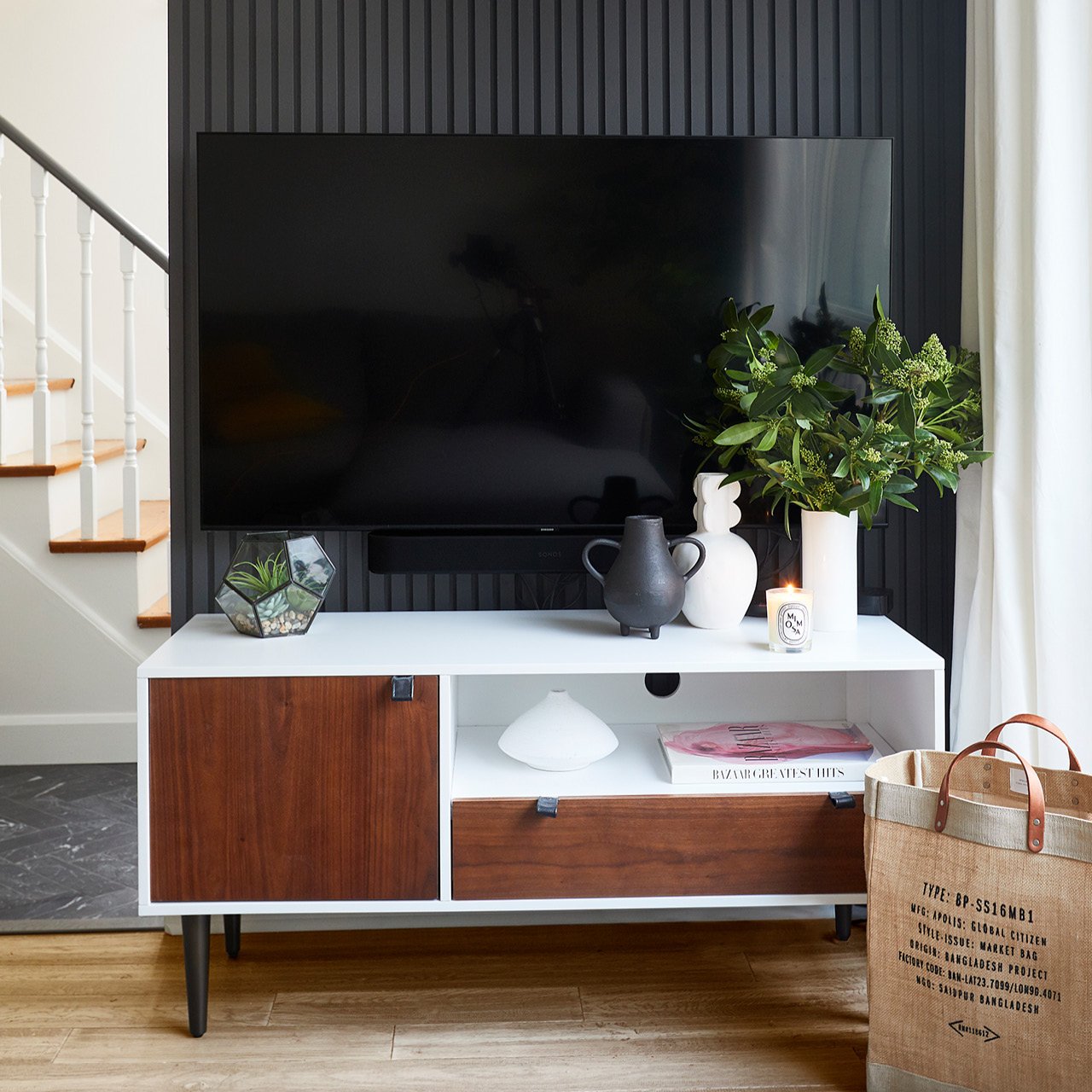 A black slat wall with a TV on a table in front of it.