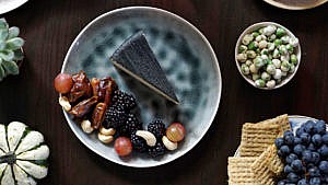 Black garlic vegan cheese on a plate with nuts and berries