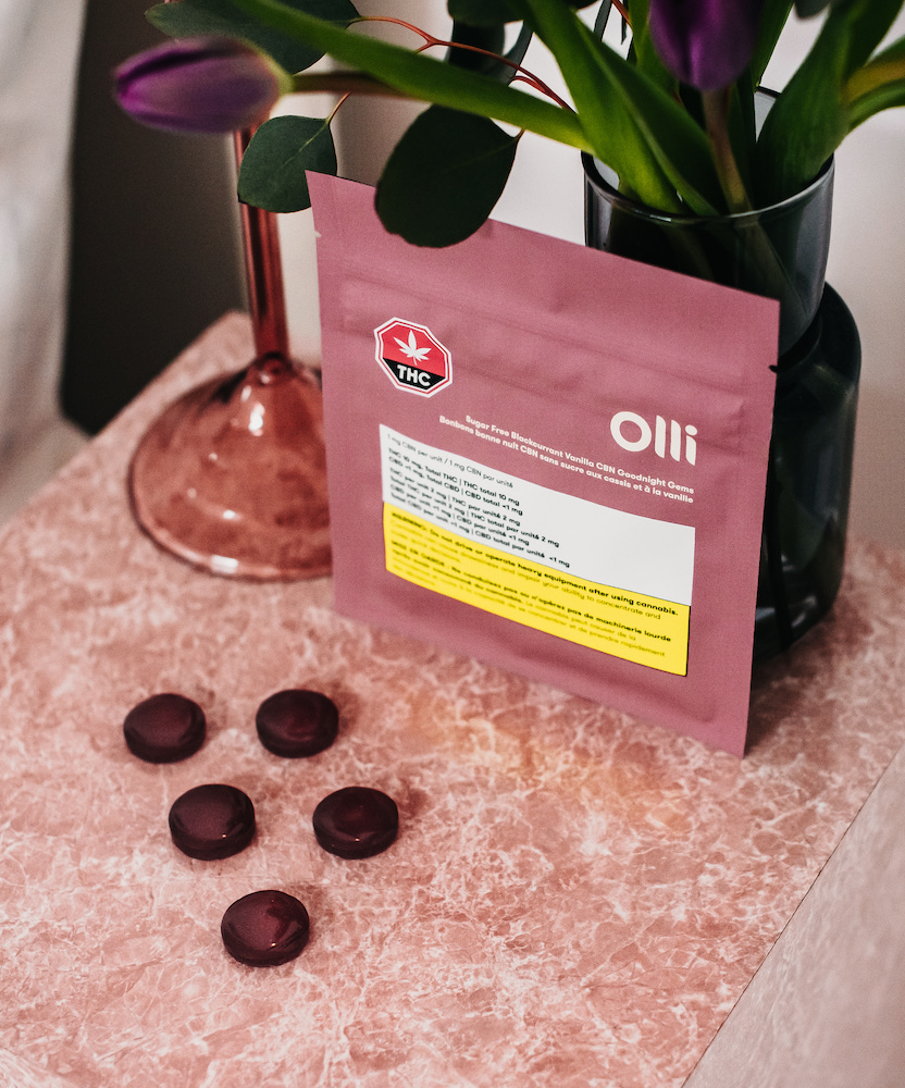 Several pieces of Olli CBN gummies laid out on a pink counter