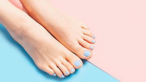 Feet with at home pedicure of blue polish on a pink and blue background.