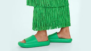 A model wearing a fringed green dress and green platform slides sandals by Mango.