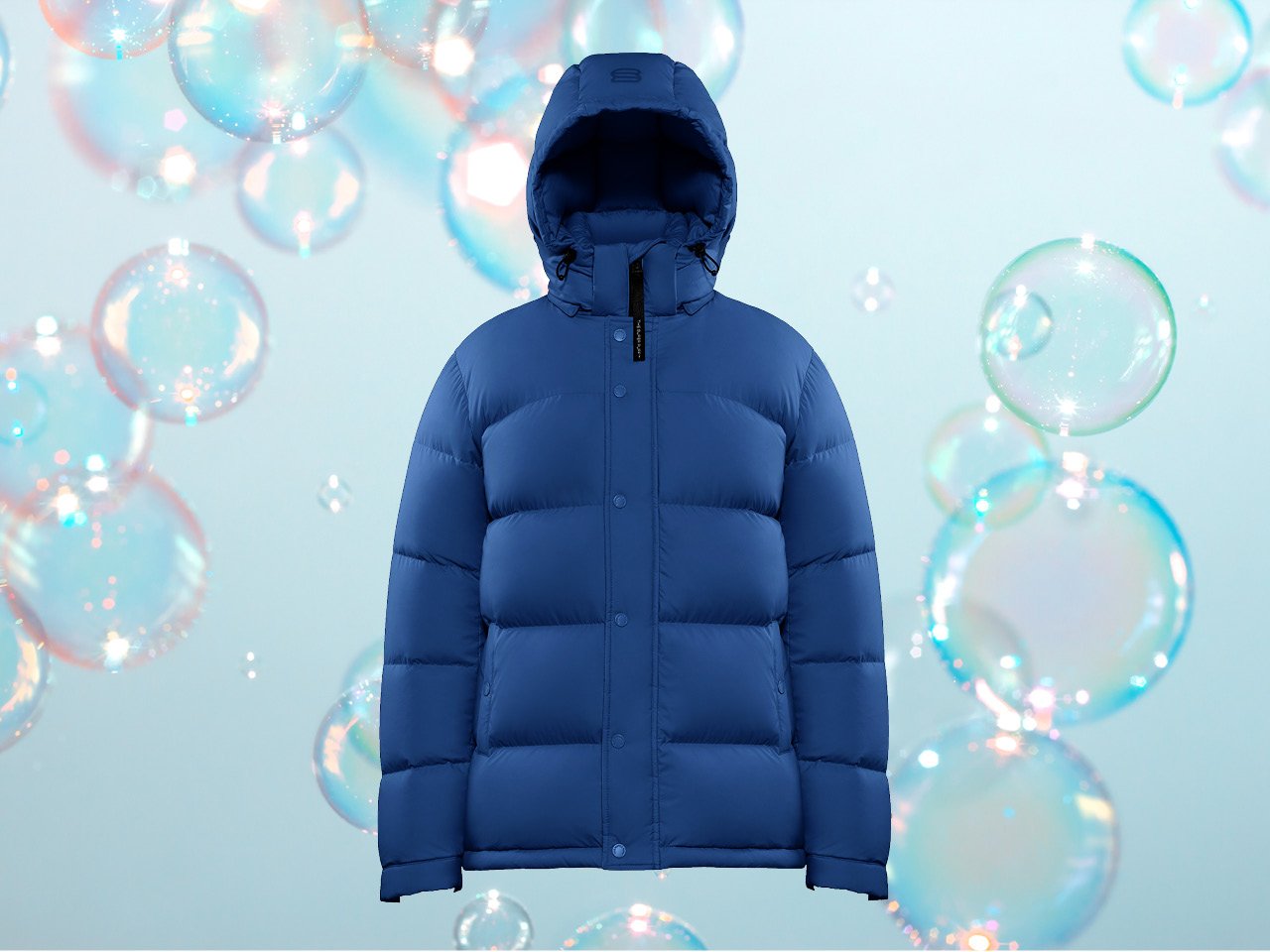 A blue puffer jacket against a blue sudsy background for an article on how to wash your puffer jacket at home.