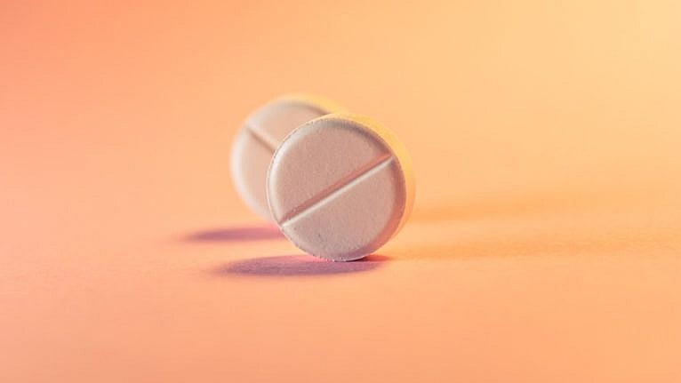 two pink pills against a soft orange background