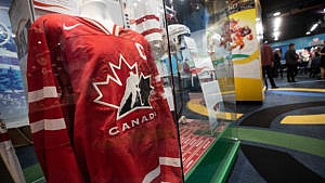 A red hockey canada jersey in a glass case surrounded by Olympic memorabilia