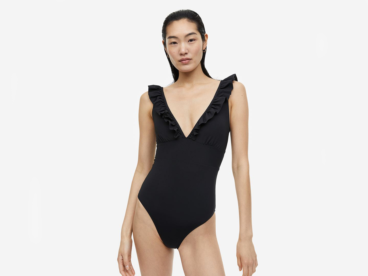 A model wearing an H&M one-piece black swimsuit with ruffled shoulders.