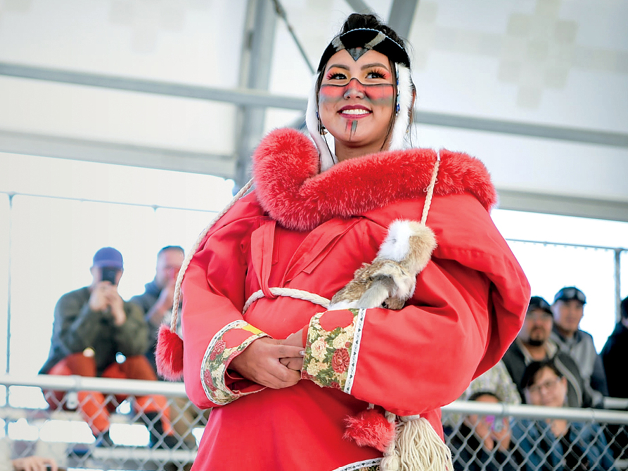 A woman wearing red Indigenous clothing poses for photos at the Great Northern Arts Festival.