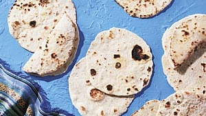 Multiple tortillas lying on a blue surface.