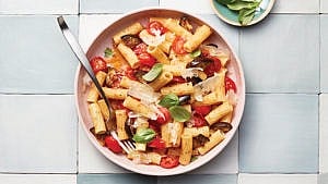 a bowl of pasta with red tomatoes.