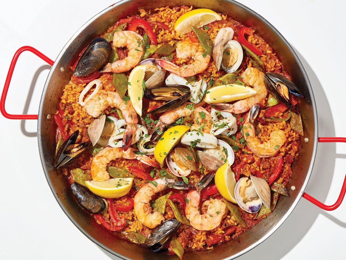 Seafood paella topped with mussels, shrimps, clams, and lemon wedges