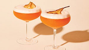 Two bartlett sour cocktails topped with slices of dried pear
