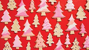 An assortment of Christmas tree-shaped holiday cookies on a red background