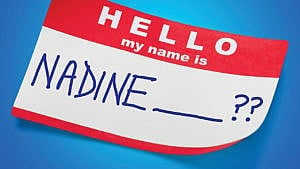 A classic "Hello, my name is" name tag in red and white with Nadine and question marks written on it in marker on a blue background