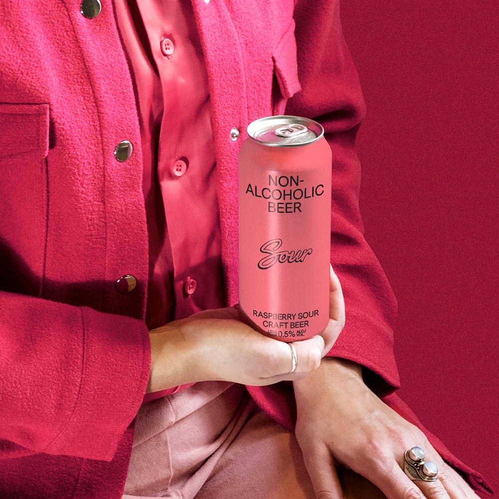 BSA (Bière Sans-Alcool) Raspberry Sour A close up of a Hand holding a pink can of non-alcoholic sour beer against a pink jacket on a pink backdrop