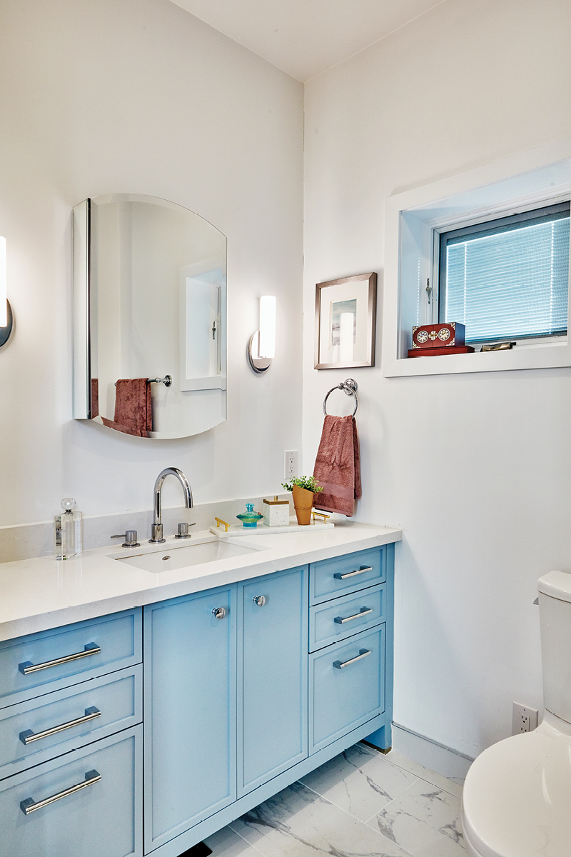 The light blue bathroom vanity with vanity mirror and marble floors