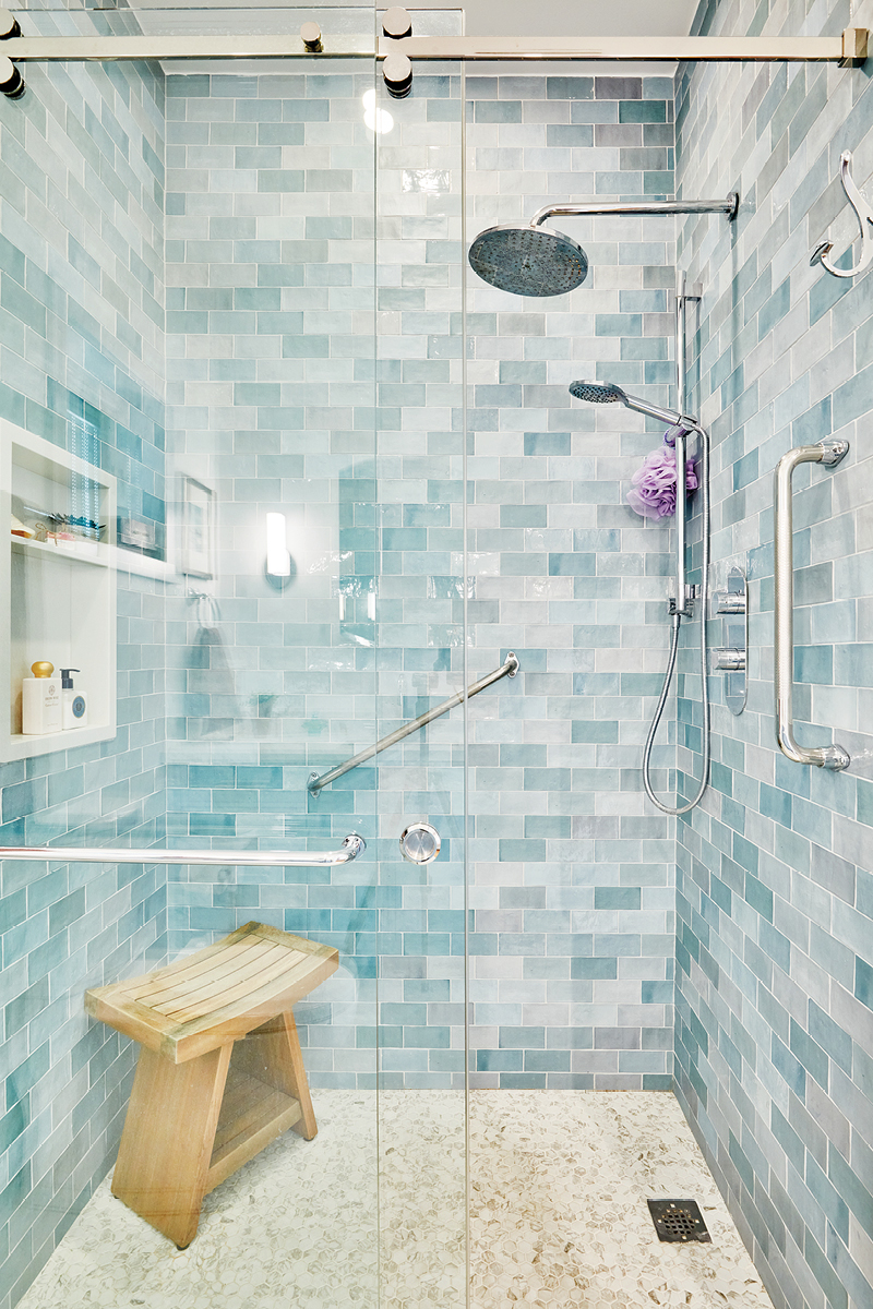 the easy-entry shower with added grab bars and light blue tiled walls