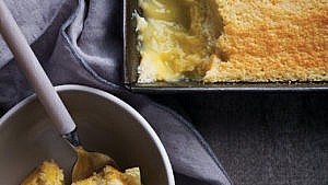 A square pan full of lemon pudding with one corner spooned out